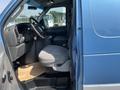 A 2005 Ford Econoline with a blue exterior showing the driver's side interior featuring a steering wheel and a gray cloth driver's seat