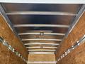 Interior view of a truck trailer showing a silver metal ceiling with overhead lights and wooden walls