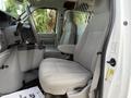Interior of a 2013 Ford Econoline showing two gray upholstered front seats and a dashboard with controls and storage compartments