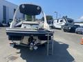 A 2013 Larson 238 boat with a sleek design features a swim platform and ladder at the rear along with twin outboard motors and a spacious cockpit area