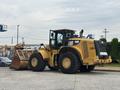 A yellow 2012 Caterpillar 980K wheel loader with a large front bucket is parked, showcasing its robust tires and prominent cab design