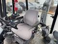 Interior view of a 2012 John Deere 310SJ with a grey driver's seat controls and levers visible on the dashboard