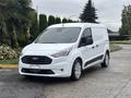 A 2019 Ford Transit Connect van in white with a black grille and circular headlights parked on a driveway