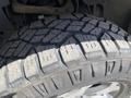 A close-up view of a rugged tire mounted on a 2014 Ford F-150 showcasing deep treads designed for traction and durability