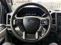 Steering wheel of a 2021 Ford F-550 with controls for audio and cruise settings and the Ford logo in the center
