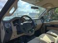 A 2013 Ford F-450 SD interior showing the steering wheel and dashboard with controls and seats in beige upholstery