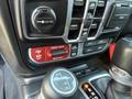 The interior dashboard controls of a 2021 Jeep Wrangler featuring buttons for different drive modes and a gear shift lever