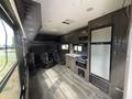 Interior of a 2021 Jayco Jay Flight featuring a kitchen area with a stove and refrigerator two chairs and cabinets