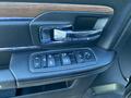 Driver's side door panel of a 2017 RAM 1500 featuring control buttons for windows and mirrors along with a chrome door handle and wood trim