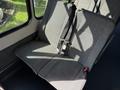 Two grey upholstered seats in a Ford Econoline with seatbelts visible