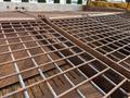 A close-up of a rusty metal grid on a vehicle's cargo area with intersecting bars and a central joint showing signs of wear and rust