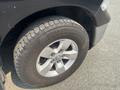 A close-up of the tire and wheel of a 2015 RAM 1500 showcasing a silver alloy rim and a rugged tread pattern