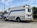 A 1994 GMC Vandura 3500 ambulance with a white exterior and blue stripes featuring rear doors and side windows