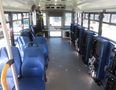 Interior of a 2020 Chevrolet Express with several blue passenger seats arranged along each side of the aisle