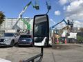 A 2018 Ford Transit-350 with a side mirror in focus parked among other vehicles in a construction area