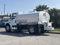 A white 2014 Freightliner M2 106 tank truck with a circular tank and dual rear wheels parked at an angle