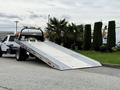 2022 Ford F600 truck with a flatbed ramp positioned at an angle for loading vehicles