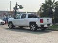 A white 2017 Chevrolet Silverado 1500 pickup truck parked showing its rear side and chrome wheels