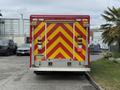 A 2007 Ford F-550 emergency vehicle with a bright red and yellow chevron pattern on the rear doors and multiple lights mounted on the back