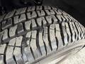 Close-up of a worn tire tread on a 2004 Chevrolet Express showing deep grooves and some dirt accumulation on the rubber surface