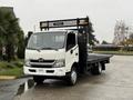 A 2015 Hino 195 flatbed truck in white with a black cargo area and a mesh safety guard at the back