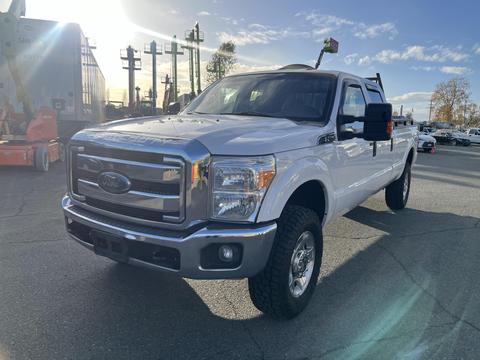 A 2016 Ford F-350 Super Duty pickup truck in white with a chrome grille and large tires parked in a lot with sunlight reflecting off its body