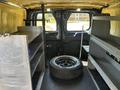 Interior of a 2016 Ford Transit 150 van with metal shelves on both sides and a spare tire in the center