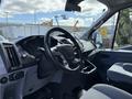 The interior of a 2016 Ford Transit showing the steering wheel dashboard and front seats designed for commercial use