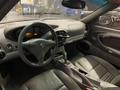 Interior of a 2003 Porsche 911 featuring black leather seats a sleek dashboard with gauges and a console with controls and gear shifter