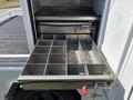 A metallic drawer with multiple compartments is partially pulled out from a work truck, designed for tool organization and storage