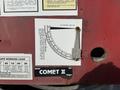 A gauge labeled "Comet II" displaying a measurement scale with a metal indicator attached to a red panel