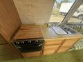 The image shows a 1976 GMC Motorhome kitchen with a wooden countertop a stove and a stainless steel sink integrated into the cabinetry