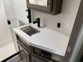 A modern countertop with a stainless steel sink and a sleek black faucet in a recreational vehicle interior