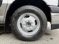 A close-up of a silver wheel with a Goodyear Wrangler tire mounted on it, featuring a distinct design with multiple lug nut holes