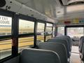 Interior view of a 2007 Freightliner B2 school bus featuring a row of grey seats with lit emergency exit signs above the windows
