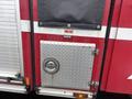 A red 2006 E-One Typhoon fire truck with a diamond plate compartment door and a circular handle