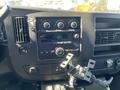 The interior dashboard of a 2013 Chevrolet Express featuring climate controls audio system and a mounted bracket for accessories