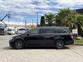A black 2014 Honda Odyssey minivan is parked with its side profile visible showcasing sleek lines and dark wheels