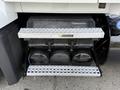 A set of metallic step plates attached to the side of a 2012 Volvo VNL providing access to the vehicle's engine compartment