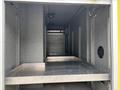 A 2010 Ford F-550 Super Duty with an empty cargo area featuring metal shelves and a rolled-up door