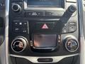 A car dashboard featuring climate control knobs and buttons, including settings for temperature, air conditioning, and fan mode, along with a display screen and hazard light button