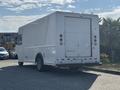 A white 2012 Ford E-450 delivery van parked on a street with a plain rear design and no visible branding