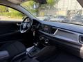 The interior of a 2018 Kia Rio5 featuring a black dashboard a steering wheel with controls a touchscreen display and a gear shift in the center console