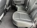 The image shows the rear seats of a 2018 RAM 1500 featuring black leather upholstery and seat belts in place with a clean design and comfortable seating layout