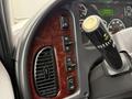 The interior dashboard of a 2018 Freightliner M2 106 featuring various control buttons and a gear shift knob in a textured wood trim design