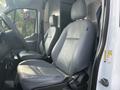 Interior view of a 2016 Ford Transit 150 showing two grey leather front seats with seat belts and a steering wheel visible in the foreground