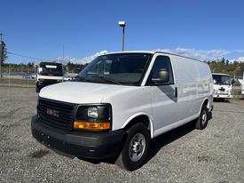 A white 2016 GMC Savana van is parked with its front angled towards the viewer showing its grille headlights and wheels