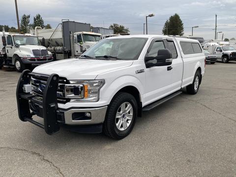 A white 2018 Ford F-150 with a black grille guard and a truck bed cap parked on a lot