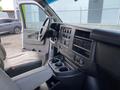 Interior of a 2023 GMC Savana showing the driver's seat dashboard and console with cup holders and control panels