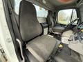 Interior of a 2015 Freightliner M2 showing driver and passenger seats in gray fabric with a flat floor and dashboard controls visible